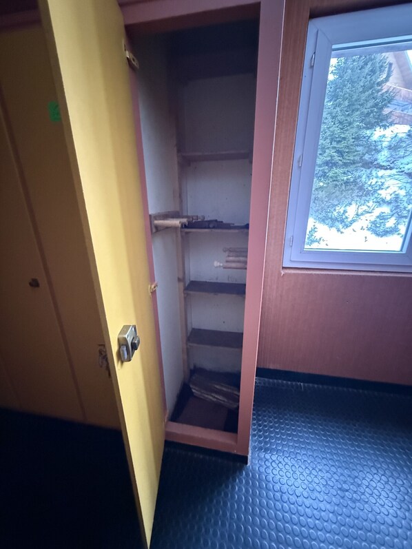 Ein schmales Zimmer mit Tür, Fenster und einem blauen, strukturierten Boden.