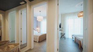 A hotel room with a bed, a desk, and a chair. There is a large window with curtains and a hanging light fixture. - 2BR Apartment in Bari, Casa Costa Sud | Private Garden + BBQ + Full Kitchen (Bari)