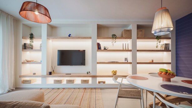 A modern living room with a flat-screen TV, wooden shelves, a dining table, and a sofa. - 2BR Apartment in Bari, Casa Costa Sud | Private Garden + BBQ + Full Kitchen (Bari)