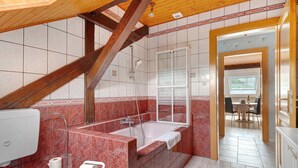 Un baño con una escalera de madera, una bañera y una ducha.