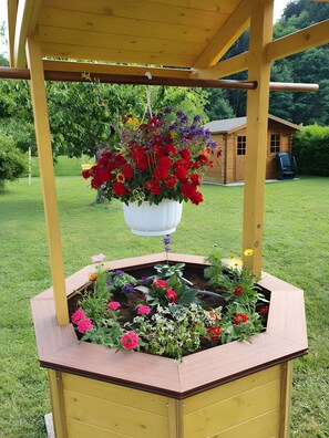 Een houten constructie met een bloembed en hangende bloemen.