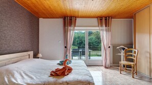 Un dormitorio con una cama grande, una silla, una mesa y vistas al exterior a través de una puerta de cristal.