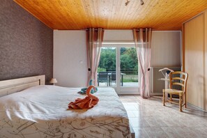 Un dormitori amb un llit gran, una cadira, una taula i vista a l'exterior a través d'una porta de vidre.