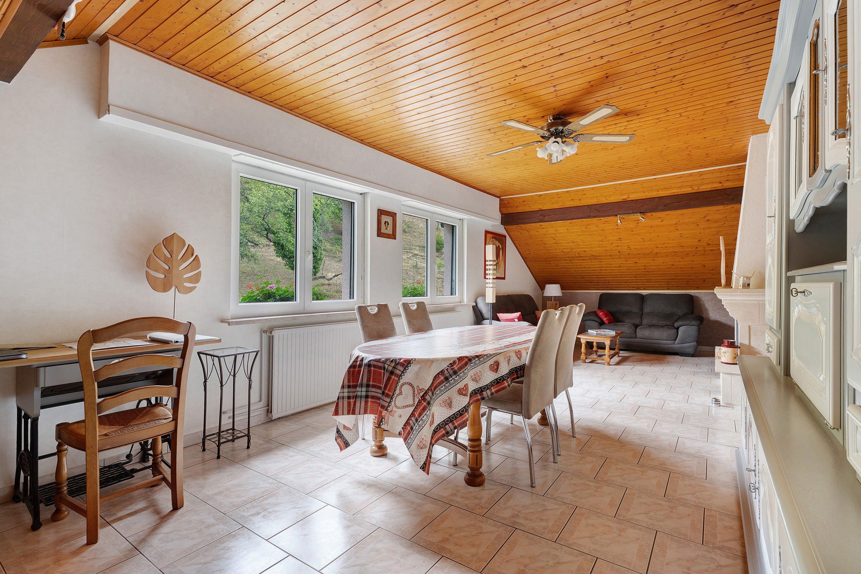 Een ruime eethoek met een houten plafond, een tafel met stoelen en uitzicht door grote ramen.