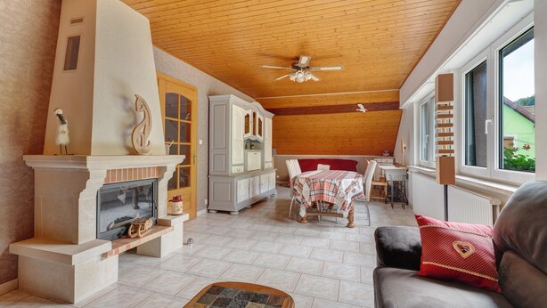 Una sala de estar acogedora con chimenea, techo de madera y comedor con mesa y sillas.