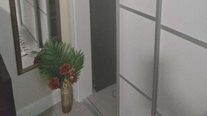 Ein Flur mit einem Spiegel, einer Blumenvase und einem Schrank mit gefalteten Handtüchern.