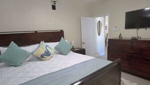A bedroom with a bed, a ceiling fan, a dresser, and a television. - Charming 1-BR solar-equipped villa + pool, gym and backyard sea view in Lucea (Lucea)