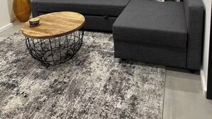 Een moderne woonkamer met een grijze modulaire bank, een ronde salontafel en een groot abstract schilderij aan de muur.