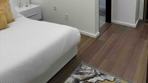 Een moderne slaapkamer met een groot bed, een nachtkastje en een deur naar een balkon.