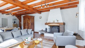 Un vaste espace de vie doté d’un plafond en bois, d’une cheminée et d’un ensemble de canapés.