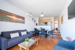 A modern living room with a sofa, a coffee table, and a dining area with chairs and a table. - 0064-GRAN RESERVA Apartment near the beach (Empuriabrava)