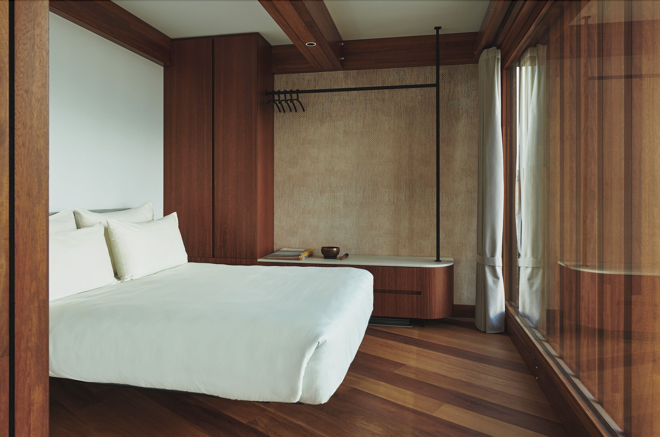 Une chambre à coucher avec un grand lit, des lambris en bois, une petite table avec un bol, et une fenêtre avec des rideaux.
