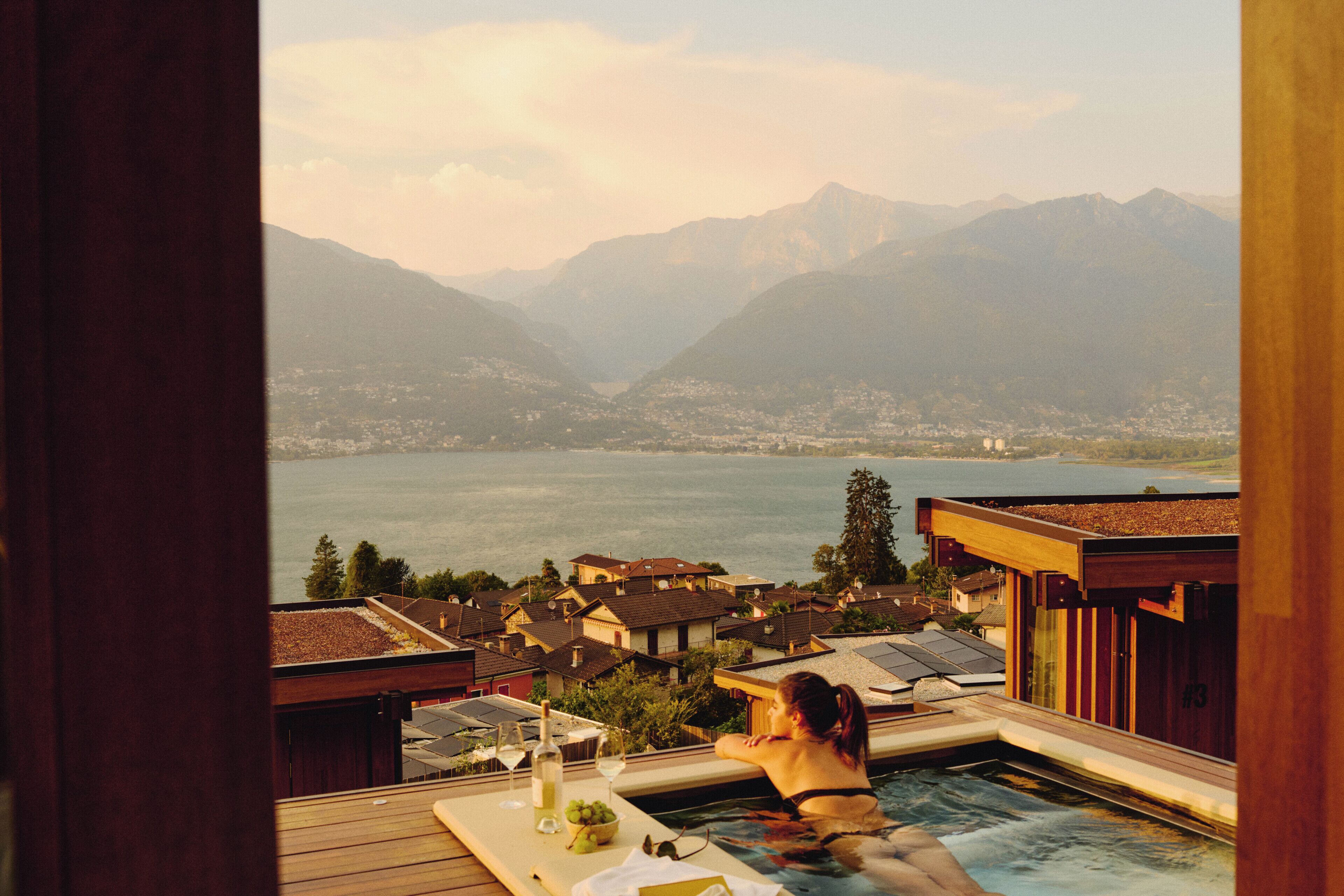 A person relaxing by a pool with a view of a lake and mountains.