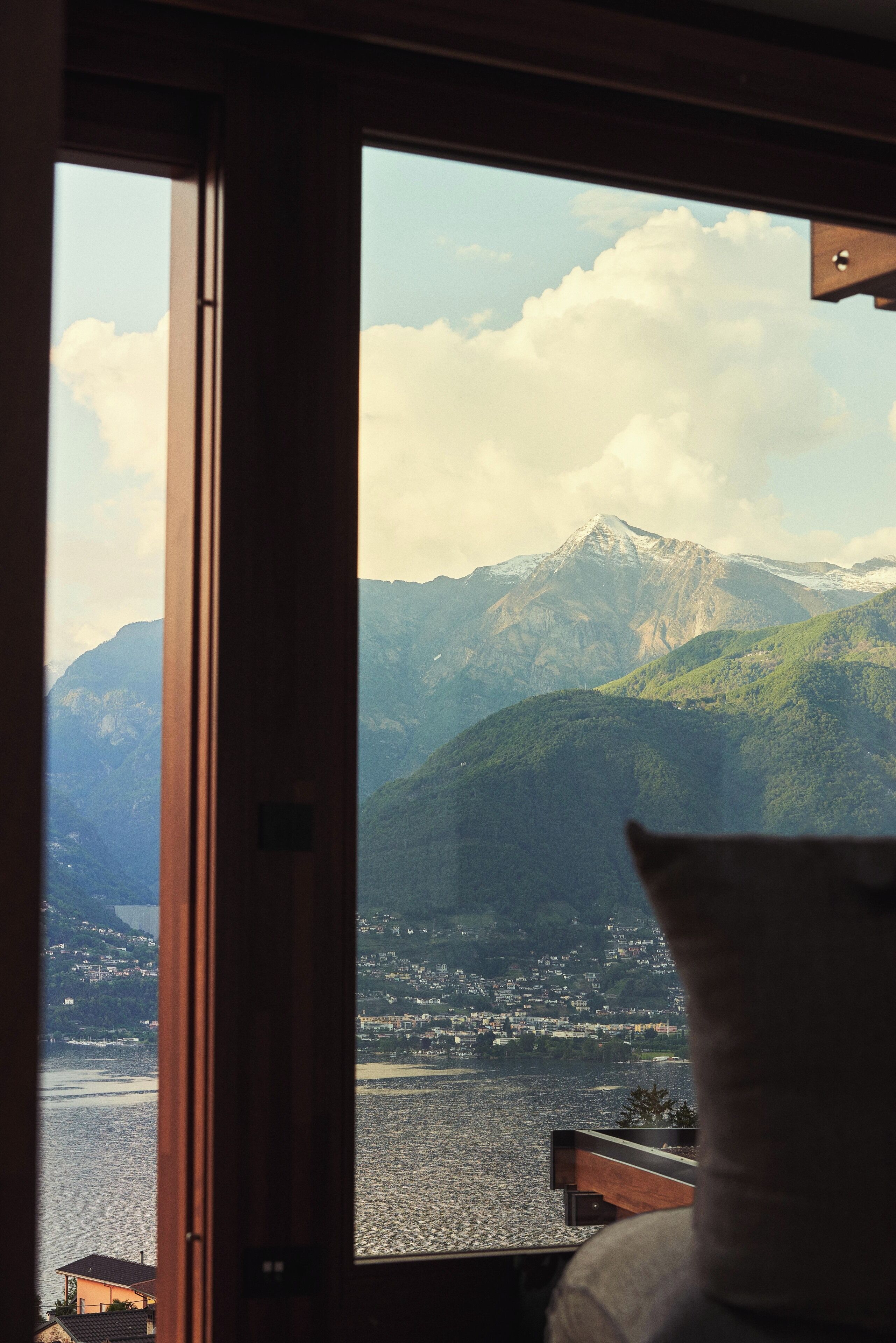 A room with a large window overlooking a mountainous landscape and a body of water.