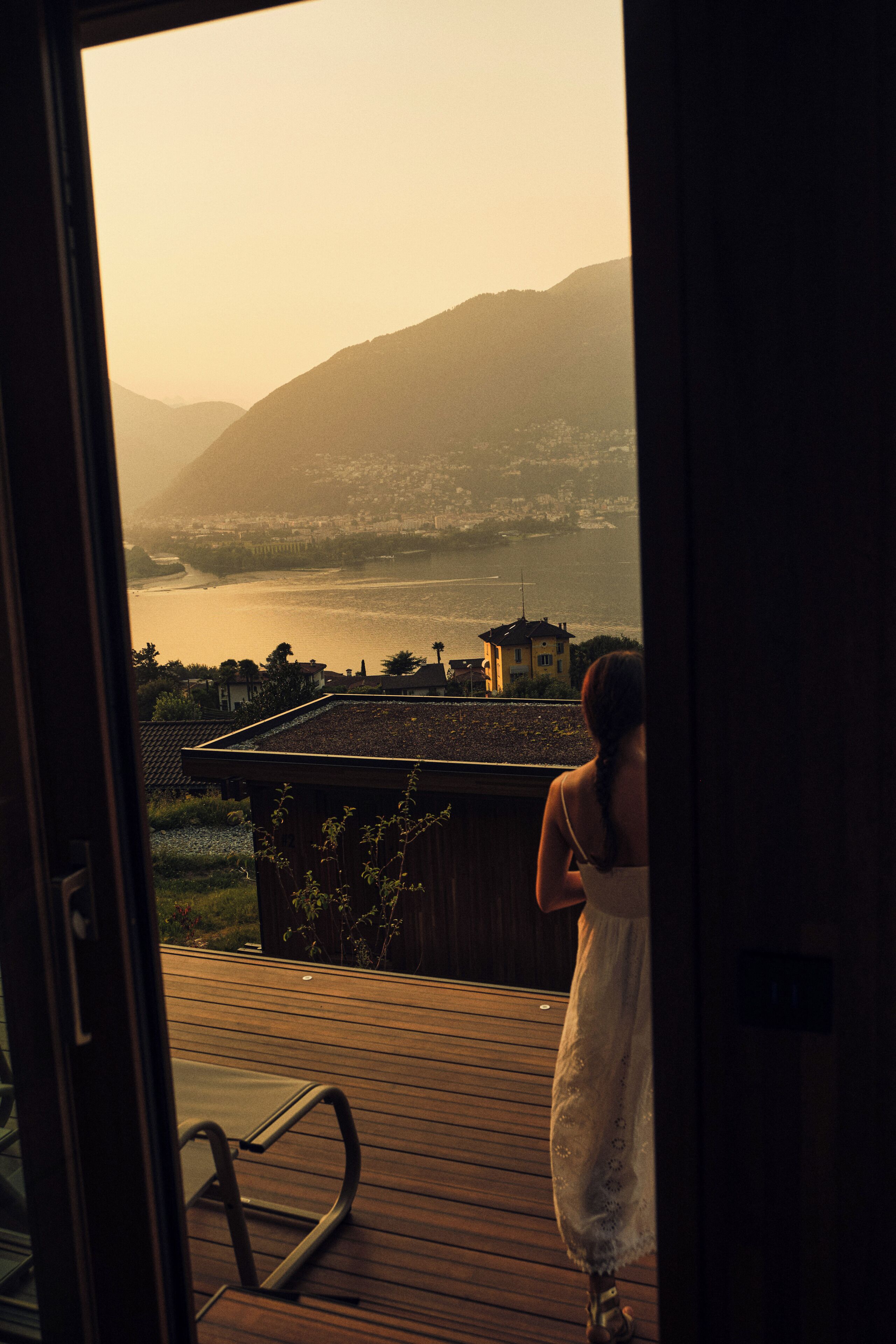 A view from a balcony overlooking a body of water and distant hills.