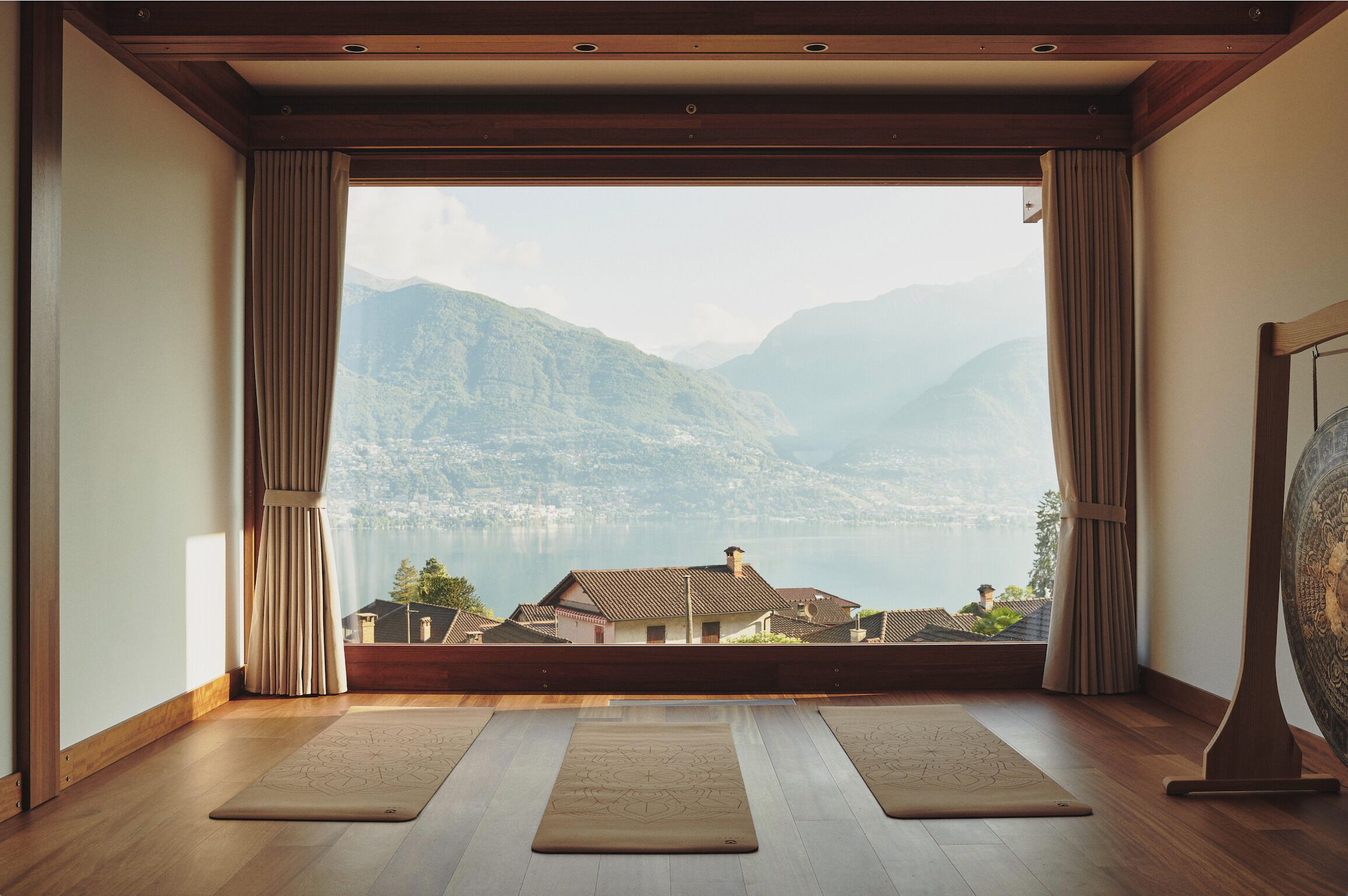 Une pièce dotée d’une grande fenêtre, d’un plancher en bois et de deux tapis de yoga.