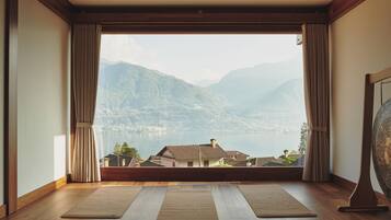 Une pièce dotée d’une grande fenêtre, d’un plancher en bois et de deux tapis de yoga.