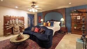 A bedroom with a bed, a blue sofa, a decorative statue, a ceiling fan, and a wooden shelf with items. - The Taj A Mini Taj Mahal at Downright Comfort! (Comfort)