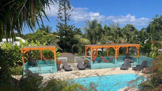 Zona de piscina con sillas de descanso y un área de estar cubierta.