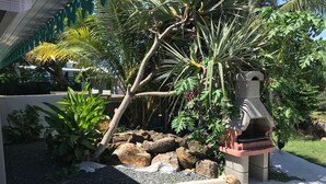 Un jardín con un comedero para pájaros, rocas y diversas plantas.