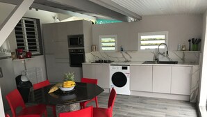 Cocina compacta con comedor, que incluye una mesa con sillas, un microondas, un horno, un fregadero y una lavadora.