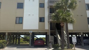 A multi-story building with a parking area, a red car, and a palm tree. - Fantastic beachfront 2-bedroom condo with AC in pleasant Tybee Island (Tybee Island)