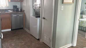 A compact kitchen with a dishwasher, a coffee maker, and a microwave. There is a door leading to another room. - Fantastic beachfront 2-bedroom condo with AC in pleasant Tybee Island (Tybee Island)
