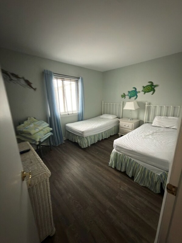 Ein Schlafzimmer mit zwei Einzelbetten, einem Schreibtisch und einem Fenster mit Vorhängen.