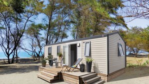 Ein kleines Strandhäuschen mit einer Terrasse, einem Stuhl und Topfpflanzen.
