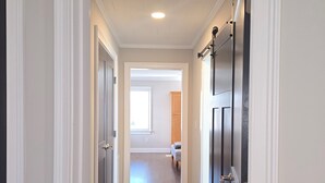 A hallway with wooden flooring, white walls, and dark doors. - Downtown Mooresville 3BR Brick Home - Fully Renovated (Mooresville)