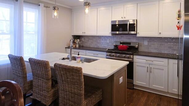 A modern kitchen with white cabinets, stainless steel appliances, and a central island with seating. - Downtown Mooresville 3BR Brick Home - Fully Renovated (Mooresville)
