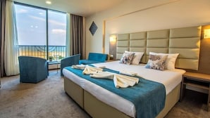 A hotel room with a large bed, a sofa, a chair, and a balcony with a railing. - MAGNIFIC   (Kranevo)