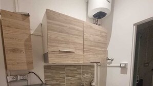 A compact kitchen with a built-in refrigerator, a sink, and wooden cabinets. - Independent Room with Private Access in Fairgrounds (Bologna)