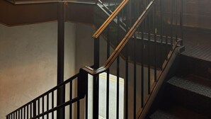 A staircase with a metal railing, a chandelier with exposed bulbs, and a wooden wall. - Westside Loft (Cookeville)