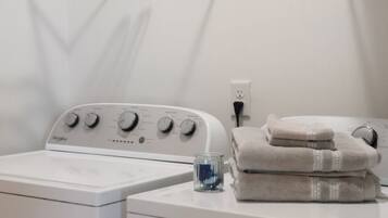 A laundry area with a front-loading washing machine, a dryer, and a hanging rack.