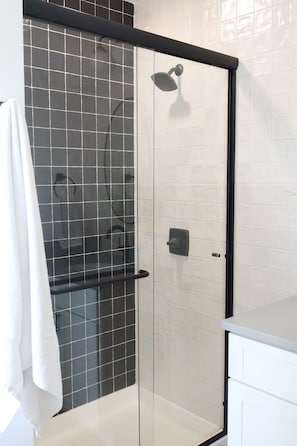 A shower enclosure with a glass door, a towel hanging on the wall, and a showerhead.