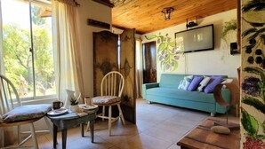Un salon chaleureux avec un plafond en bois, un canapé bleu, une commode en bois et une table à manger avec des chaises.