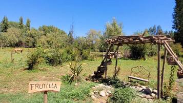 A rustic outdoor area with a wooden sign labeled "FRUTILLA" and a wooden structure resembling a pergola.