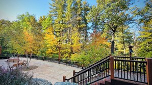 A wooden staircase leading to a deck surrounded by autumn foliage.