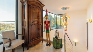 Una stanza spaziosa con un'ampia credenza in legno, una sedia, un gnomo decorativo e un lampadario.