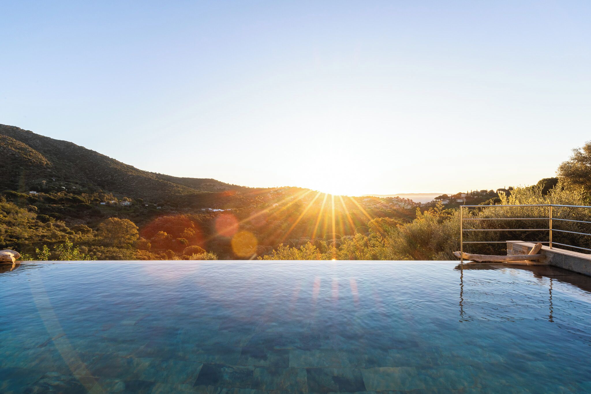 A clear view of a swimming pool with a sunlit landscape in the background.