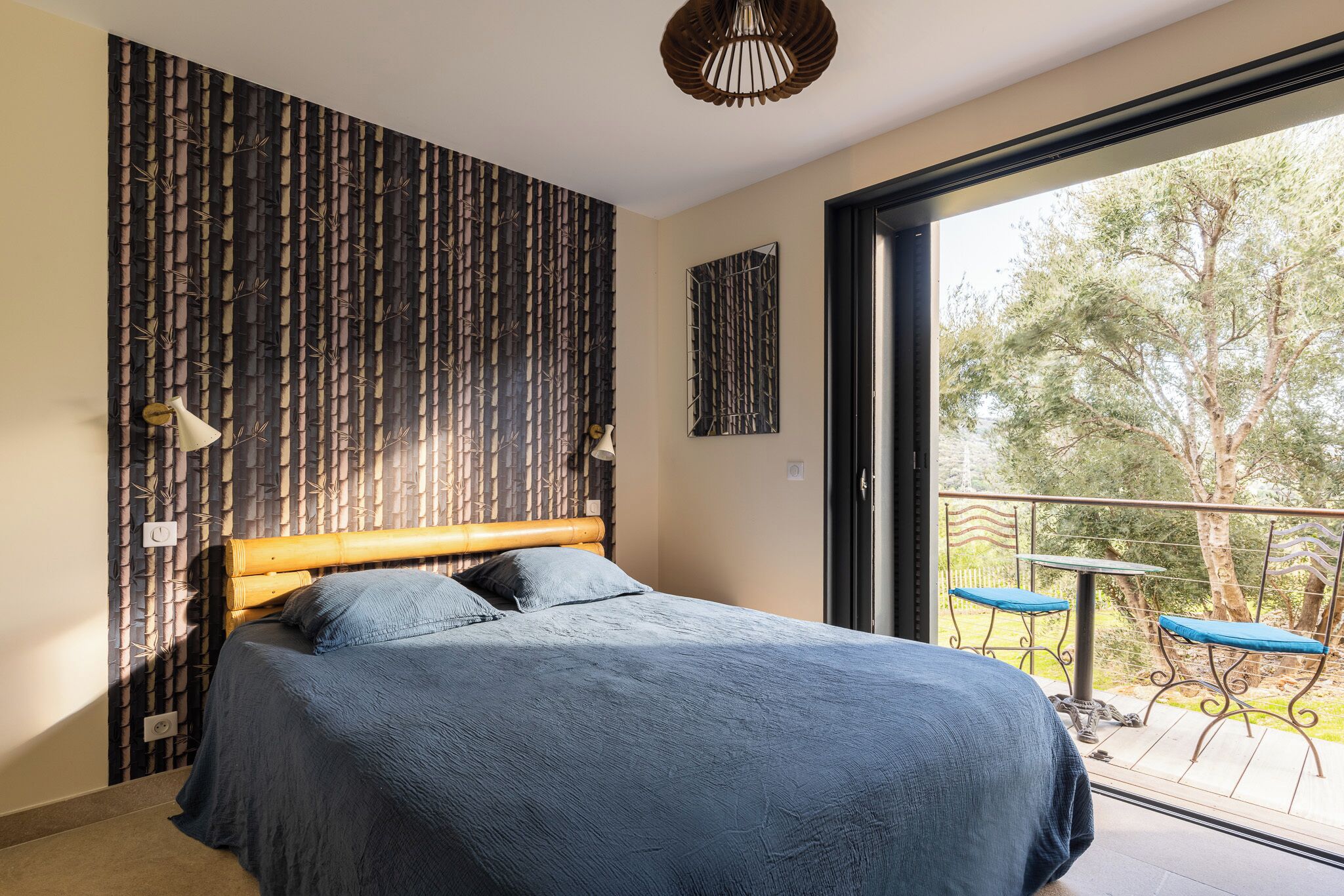 Un dormitorio con una cama grande, vistas al exterior y un balcón con sillas.