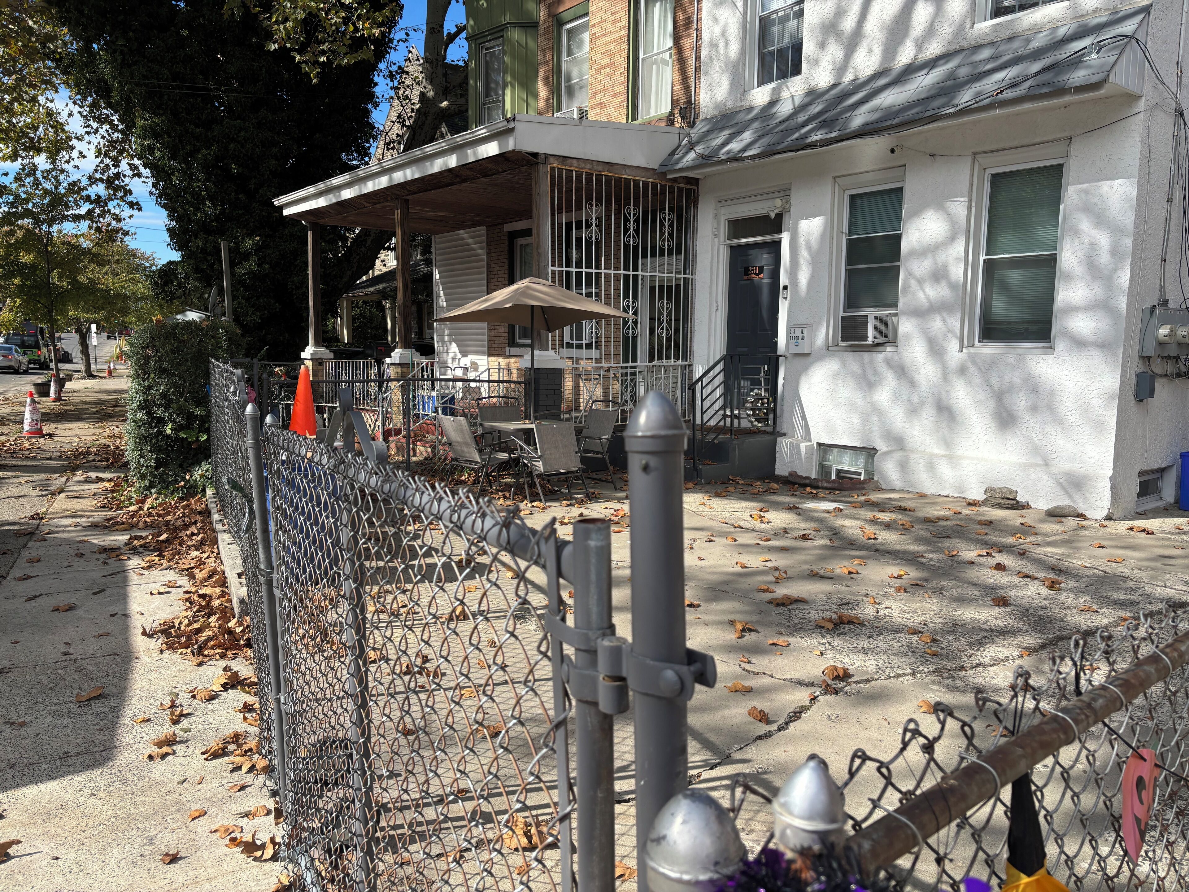 A residential building with a fenced yard, a covered porch, and a visible front door.