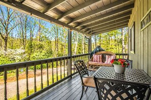 Une véranda abritée avec une table et des chaises, un canapé en osier et une plante en pot.
