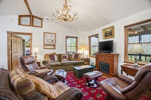 A living room with a fireplace, leather chairs, a sofa, a television, and framed artwork on the walls. - Secluded Franklin Cabin with Mountain Views (Franklin)