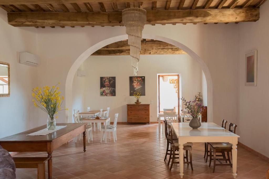 Un vaste espace dédié à la salle à manger, avec une grande table et des chaises, une porte en arc de cercle et un lustre.