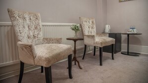 Two plush armchairs with tufted backs, a small round wooden table with a vase, and a coffee station with a kettle and cups. - The Cherry Tree B&B Hotel (Eastbourne)