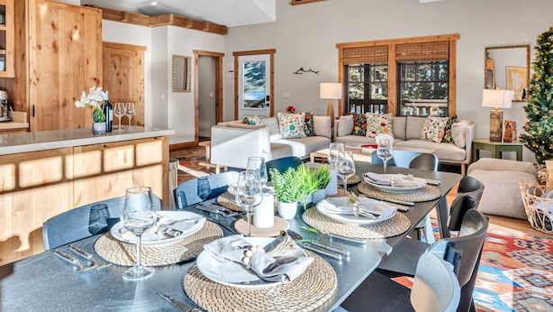 A dining area with a long table set for a meal, surrounded by chairs and a sofa. - Camp Carnelian |  Walk to Lake Tahoe + Quiet Deck (Carnelian Bay)