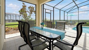 Eine verglaste Terrasse mit Pool, Sitzgelegenheiten im Freien und Blick auf die Landschaft.