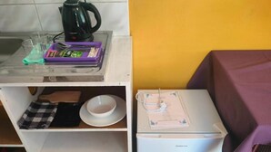 Una cocina compacta con cafetera, un refrigerador pequeño y una mesa con un menú.